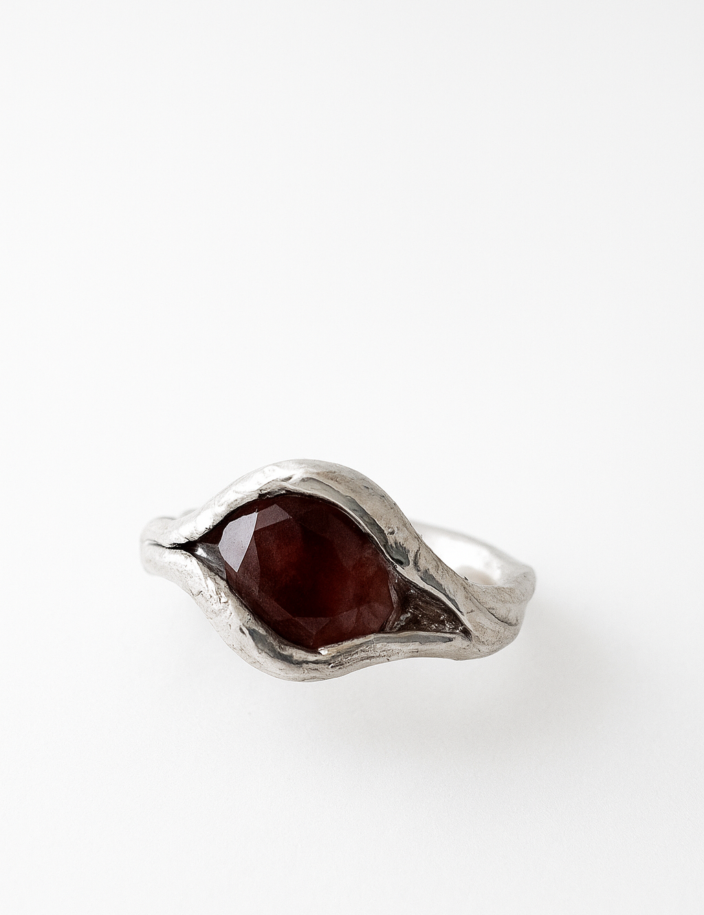Primer plano del anillo de plata esterlina con piedra del sol ovalada engastada de forma orgánica en la banda, visto desde arriba.