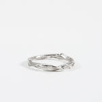 Anillo Nido Incrustado en plata esterlina con pequeño diamante de laboratorio incrustado en una banda orgánica retorcida, sobre fondo blanco.