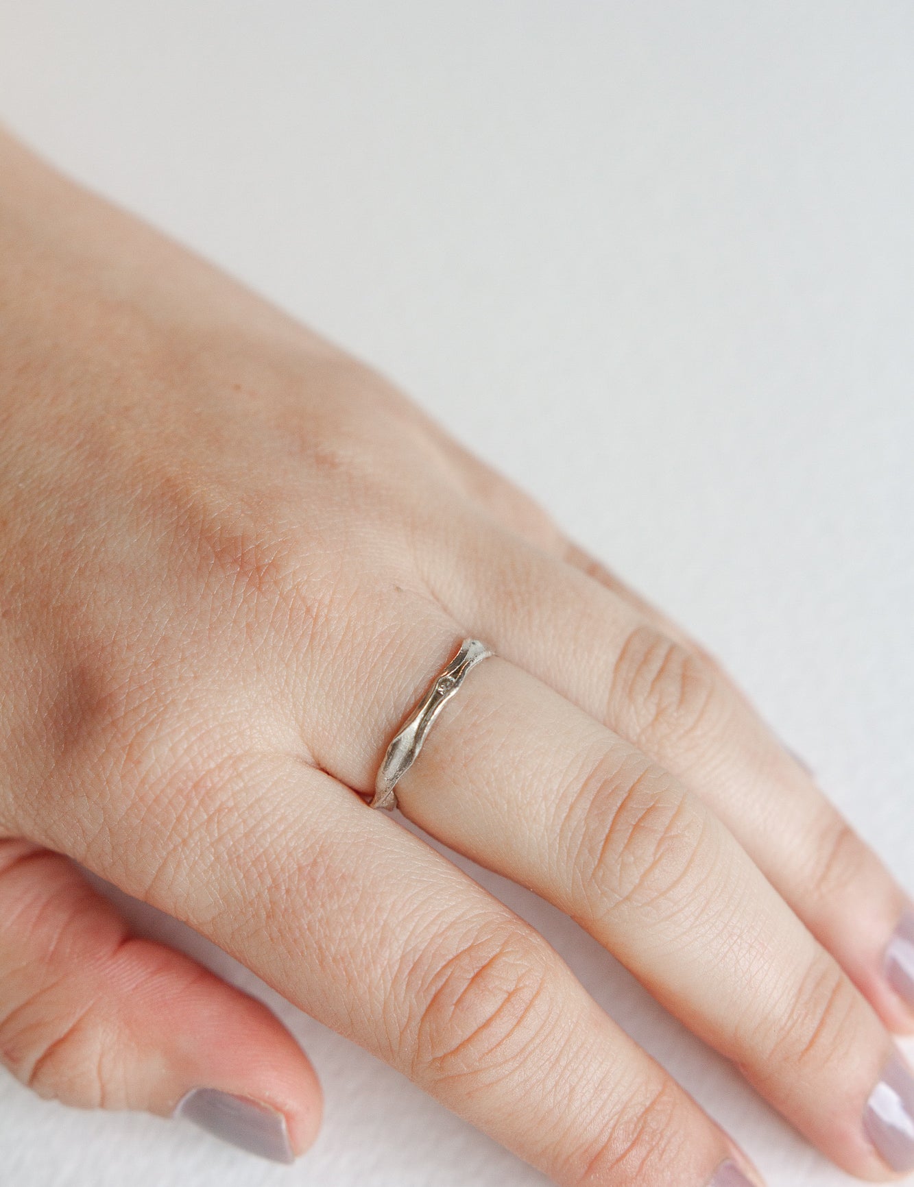 Anillo Nido en plata esterlina con diamante de laboratorio puesto en una mano, fotografiado sobre superficie neutra.