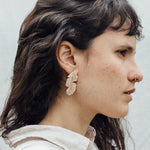 Retrato de una mujer con los aretes Hojas de Plátano—variantes pintadas a mano en verde salvia y rust con granulación de vidrio en bronce bañado en oro