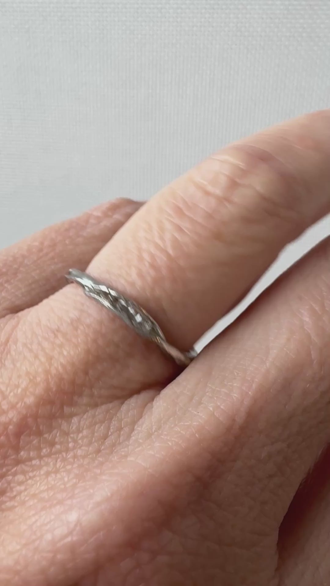 Anillo artesanal de plata con diamantes de laboratorio, colocado en un dedo, captado desde un ángulo lateral.