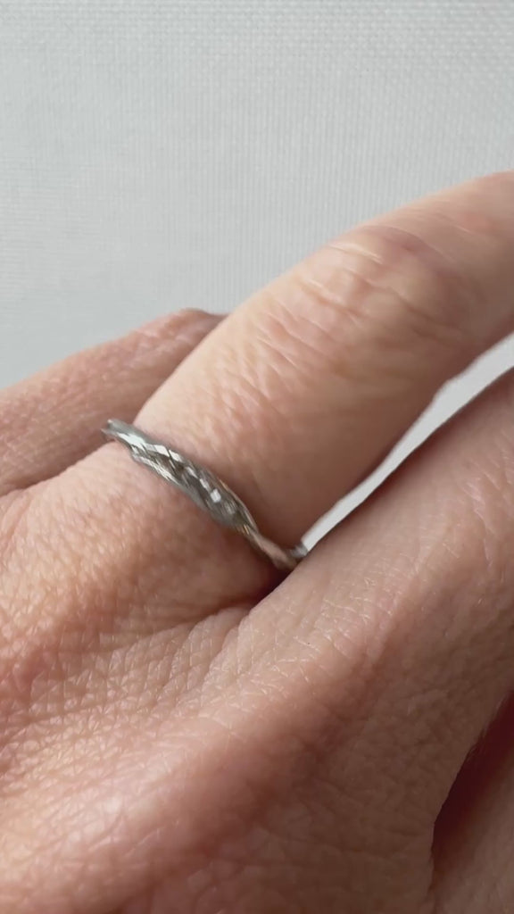 Anillo artesanal de plata con diamantes de laboratorio, colocado en un dedo, captado desde un ángulo lateral.